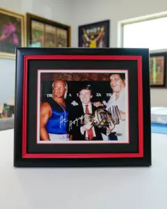 Framed signed photo of wrestling legends displayed in a memorabilia frame.