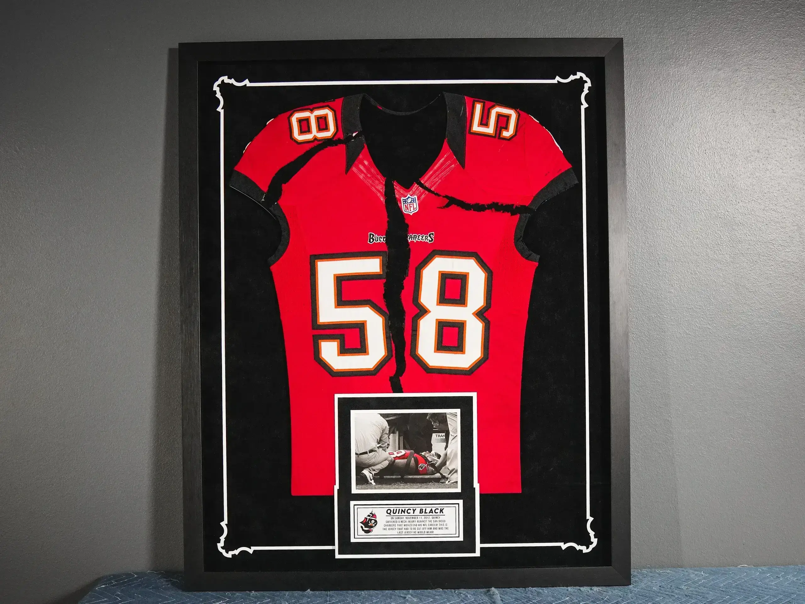 A framed jersey and photo of the tampa bay buccaneers.