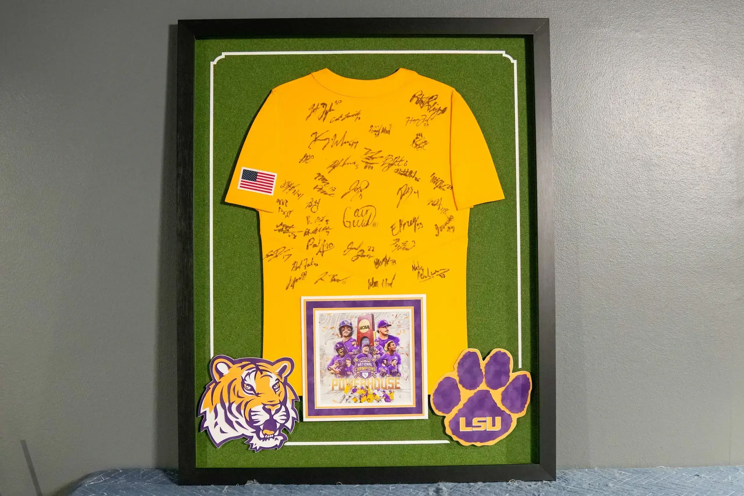 A framed lsu shirt with autographs of players and coaches.
