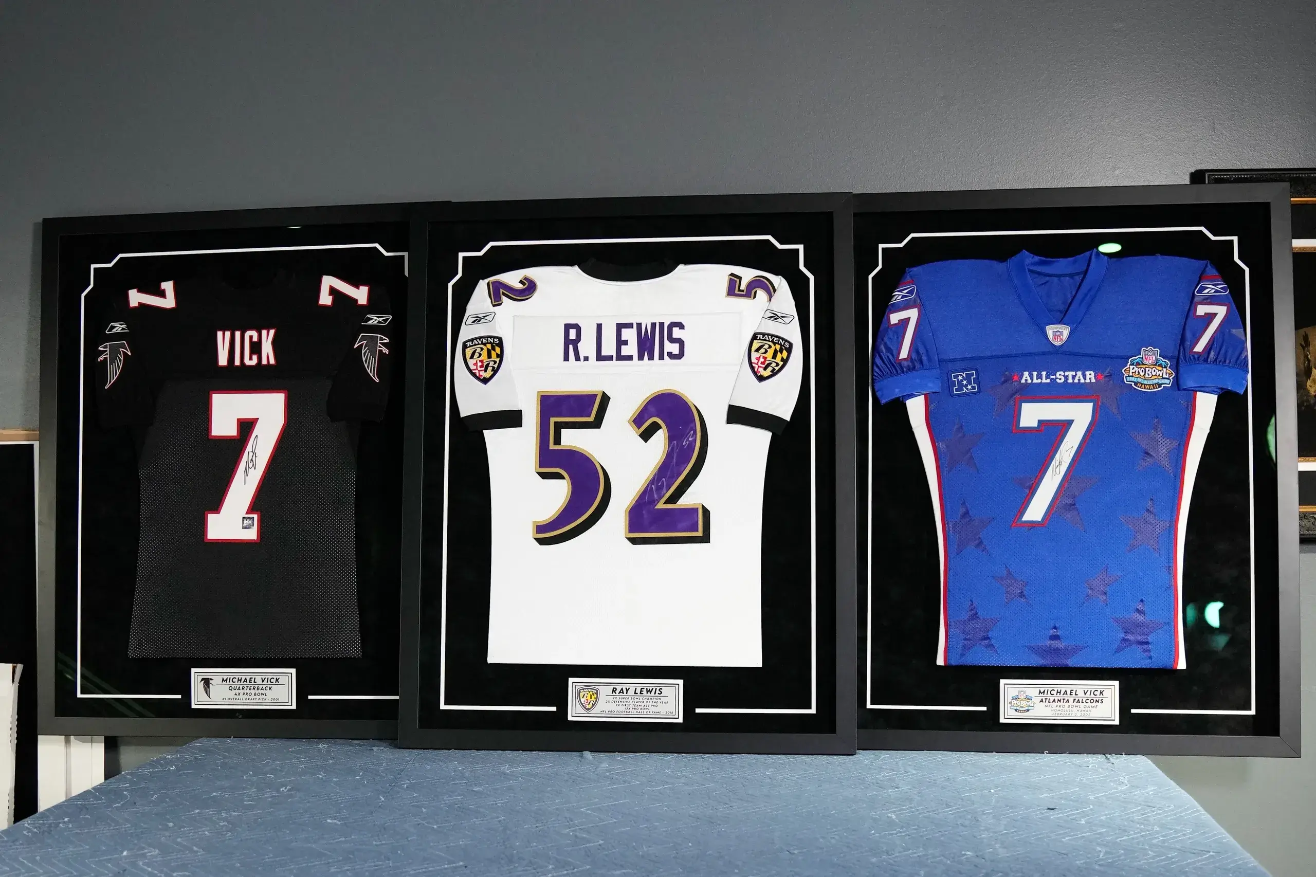 Three framed jerseys of the baltimore ravens.