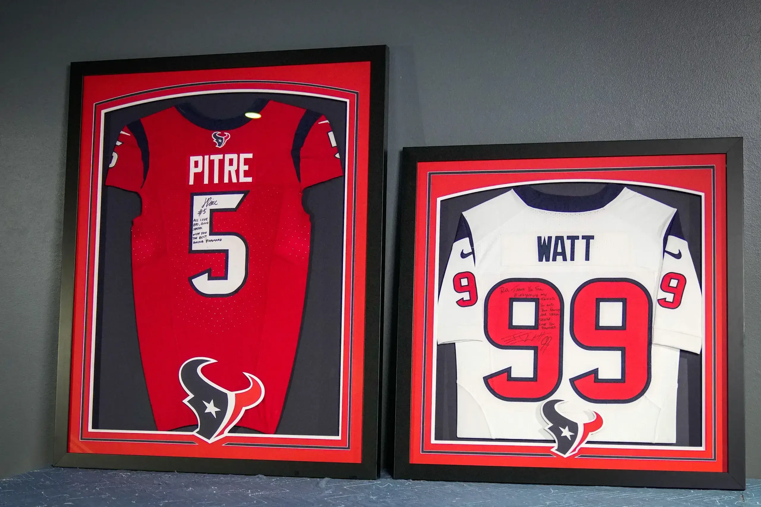 Two framed jerseys are displayed on a shelf.